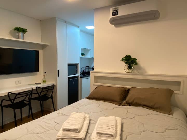 Cama, bancada e acesso à cozinha do studio próximo ao metrô Ana Rosa